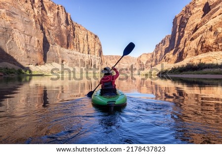 Adventurous Woman on a Kayak paddling in Colorado River. Glen Canyon, Arizona, United States of America. American Mountain Nature Landscape Background. Adventure Travel Royalty-Free Stock Photo #2178437823