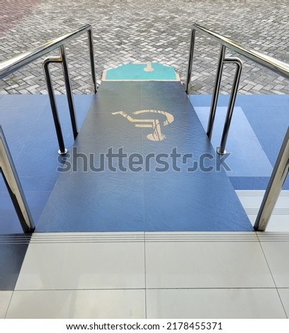 Ramp way for support wheelchair disabled people. Using wheelchair ramp Selective focus. with stainless steel handles with handicap markings to support wheelchair disabled people.


