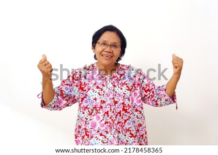 Overjoyed asian elderly woman rising hands up. Senior woman with winning hand gesture