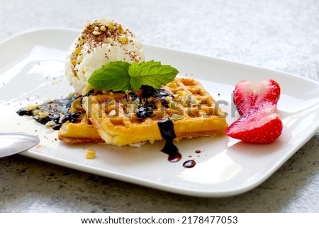 ice cream with Belgian waffles, strawberries, fresh mint, chocolate topping and nuts
