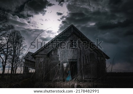 Old wooden house,dramatic clouds at night. Abandoned Haunted Horror House.Near is stand trees at night.Toned.