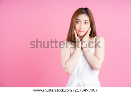 Image of young Asian woman posing on pink background