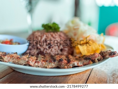 Close up of roast beef with gallo pinto and pico de gallo, Nicaraguan food served on wooden table, Plate with roast beef and rice served on wooden table Royalty-Free Stock Photo #2178499277