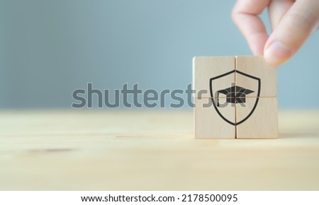 Insurance for education concept. Protection and study, education security sign. The wooden cubes with protection and security of education symbols on beautiful grey background with copy space. 