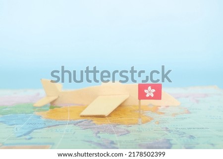 Selective focus of Hong Kong flag in blurry world map and wooden airplane model. Hong Kong as travel and tourism destination concept.