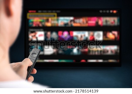 man relaxing at home in evening and watching TV. Multimedia streaming concept. VoD content provider. Video service with internet streaming multimedia shows, series. Royalty-Free Stock Photo #2178514139