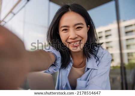 Happy charming brunette woman reach her hand to camera . Dark-haired chinese lady look with smile and doing selfie. Concept of technology 