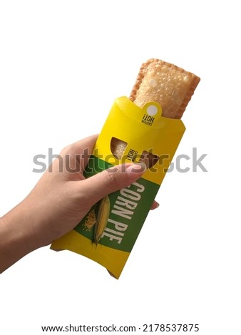 Hand holding corn pie isolated on white background