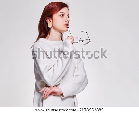 Redhead young woman hold in hand eyeglasses near face standing on isolated white backgroung, copy space. learning and teaching concept or make announcement advertisement