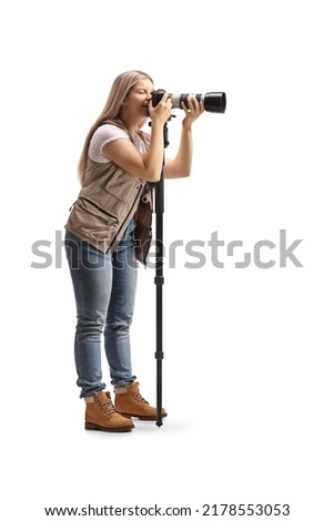 Full length shot of a female photo journalist using a camera on a stand isolated on white background