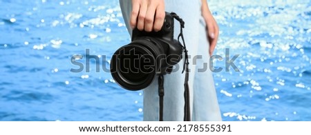 Professional photographer with modern camera and blurred view of beautiful sea on sunny day. Banner design
