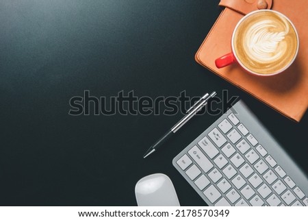 Top view, Dark Office desk with keyboard computer, cup of coffee, pen, mouse and notebook, copy space, Mock up.	

