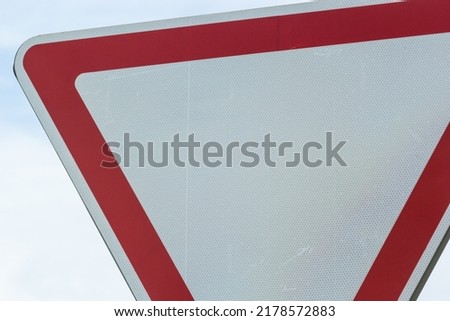 Road sign against the sky. White triangle with red border. Signal, Give way. Summer day.