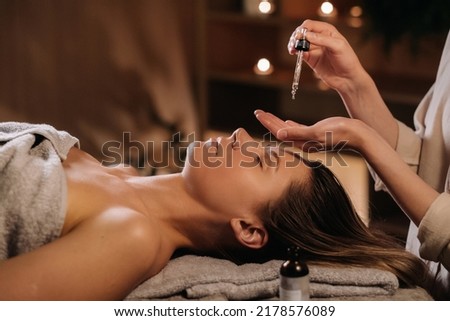 A female cosmetologist holds a pipette with essential oil before aromatherapy and massage to the patient. aromatherapy.Close-up. Royalty-Free Stock Photo #2178576089