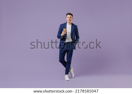 Full size young successful employee business man lawyer 20s wear formal blue suit white t-shirt hold takeaway delivery craft paper brown cup coffee isolated on pastel purple background studio portrait Royalty-Free Stock Photo #2178585047