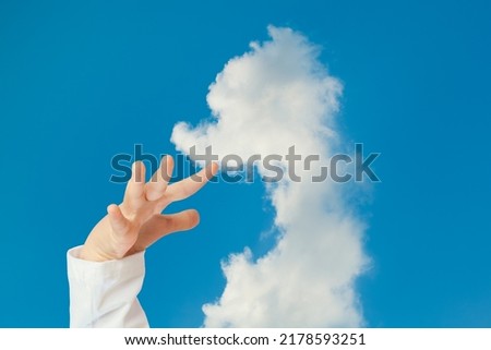 Child hands trying to touch to animal shaped cloud in the blue sky. Concept idea of inspiration, imagination, hope and dream of child.
