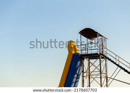Observation wooden tower with a lifeguard boat on the beach against the blue sky.