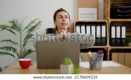 Middle age hispanic woman business worker tired stretching arms at office