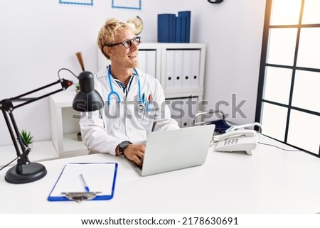 Young caucasian man wearing doctor uniform working at clinic