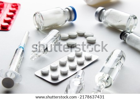 Medicines on a white background: tablets in blister and loose, ampoules with liquid and powder, syringe Royalty-Free Stock Photo #2178637431