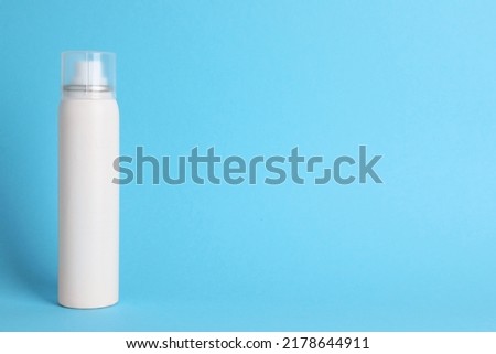 Bottle of dry shampoo on light blue background, space for text