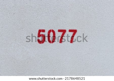 Red Number 5077 on the white wall. Spray paint.
