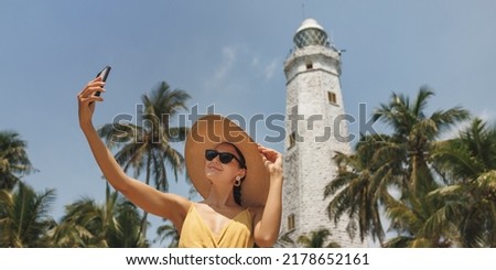 Sri Lanka tourist girl on holiday taking selfie photo with phone at famous place Dondra Lighthouse, Asian tourism attraction.