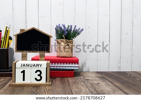 January 13 calendar date text on white wooden block with stationeries on wooden desk. Calendar date concept.