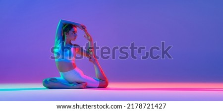 Flyer. Studio shot of young flexible girl in fitness sport uniform practicing isolated on gradient pink-purple background in neon light. Modern sport, action, fitness, yoga, motion, youth concept.
