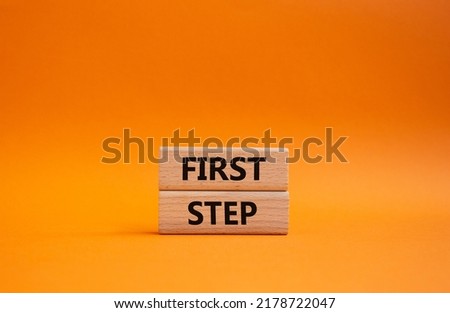 First step symbol. Wooden blocks with words 'First step'. Beautiful orange background. Business and 'First step' concept. Copy space.
