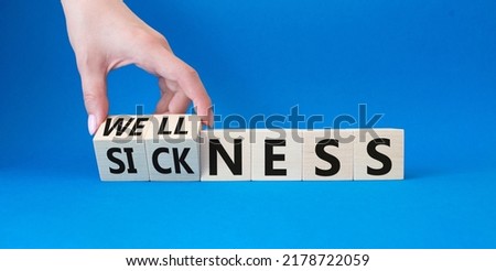 Wellness and Sickness symbol. Hand turns a cube and changes the word sickness to wellness. Beautiful blue background. Businessman hand. Business and wellness and sickness concept. Copy space Royalty-Free Stock Photo #2178722059