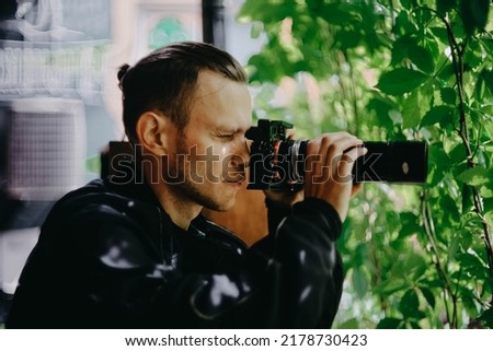 male spy private detective with a long lens camera is watching in a cafe.