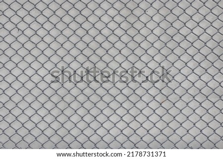 chain link fence wire mesh steel metal background with white concrete wall, secured property, Abstract background.
