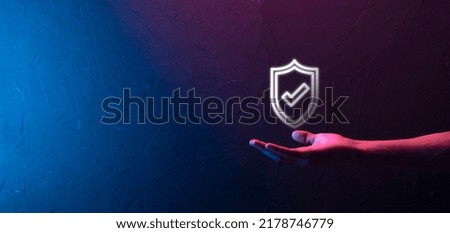 Male hand holding protect shield with a check mark icon on blue background. Protection network security computer and safe your data concept
