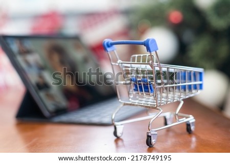 toy trolley and a Christmas tree on background. Copy space - concept of online shopping, ordering goods, home delivery, new year 2023, decoration, preparation
