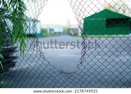 Hole in the fence. Mesh wire boundary. Steel mesh barrier fence. Chain link fence with Hole.  Royalty-Free Stock Photo #2178749925