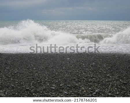 macro photo with a decorative natural background of a seascape with white foam of large waves near the shore with pebbles for design as a source for prints, posters, wallpaper, interiors, advertising