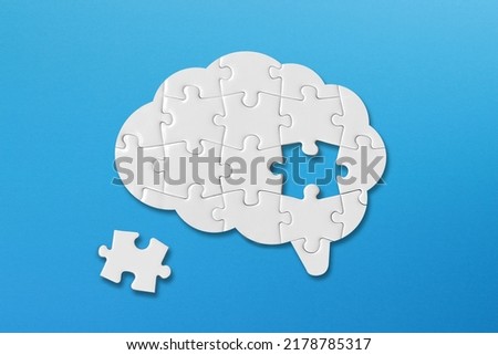 Brain shaped white jigsaw puzzle on blue background, a missing piece of the brain puzzle, mental health and problems with memory Royalty-Free Stock Photo #2178785317