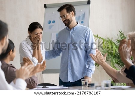 Smiling businessman congratulate excited female employee with job business success or work promotion at meeting. Diverse colleagues applaud. Happy male boss greeting woman worker with employment. Royalty-Free Stock Photo #2178786187