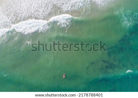 aerial shot of a surfer with a red board waiting for a wave