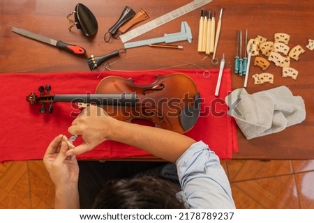 Top view of a worker in a musical instrument repair workshop repairing a violin Royalty-Free Stock Photo #2178789237
