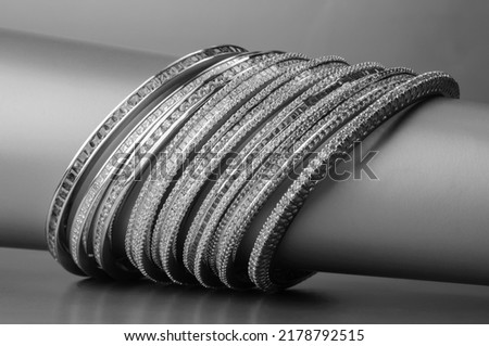 Silver Bangles Jewelry or Jewellery Isolated on Cylindrical Stand Exclusively for Women. Monochromatic Background. Royalty-Free Stock Photo #2178792515