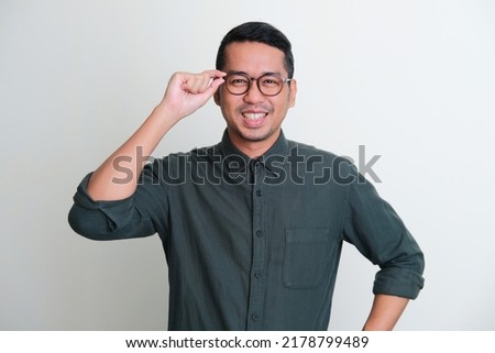 Adult Asian man smiling confident with hand touching his glasses frame