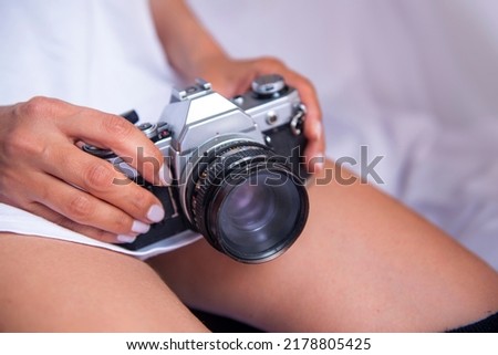 young woman holding analog camera on her lap