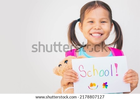 Back to school. A kindergarten student holding a school sign smiling.