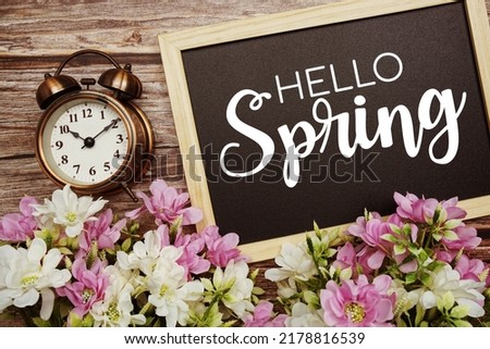 Hello Spring typography text written on wooden blackboard with flower bouquet decorate on wooden background