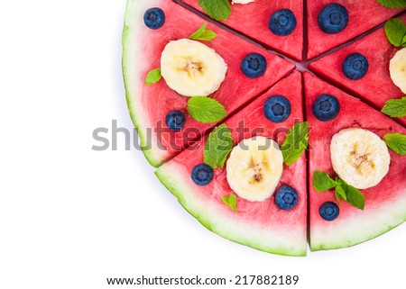Sliced juicy watermelon pizza isolated on white, closeup view from above. Ingredients are watermelon, blueberries, banana, mint.