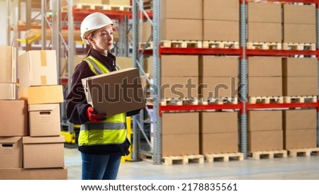 Warehouse worker. Woman works in warehouse. Girl with box. Girl in uniform of warehouse worker. Storekeeper in reflective vest. Selective focus. Storage logistics. Woman in white helmet Royalty-Free Stock Photo #2178835561