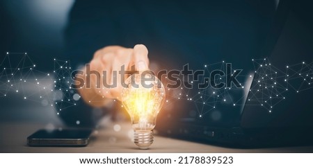 Businessman hand holding light bulb with icons and working on the desk, Creativity and innovation are keys to success.Concept of new idea and innovation with energy and power , working at home,
