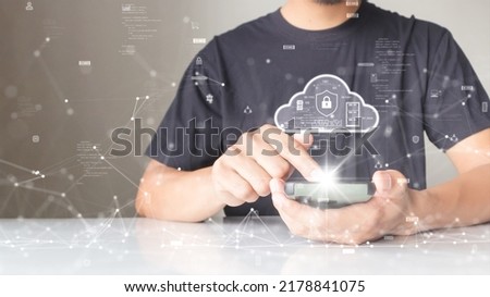 A person is connecting to the Internet through a smartphone to download and upload data to cloud computing technology with cybersecurity protection. with a small binary polygon icon on the background. Royalty-Free Stock Photo #2178841075
